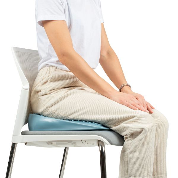 Person som sitter på kilformad sittkudde, ergonomiskt NPF-hjälpmedel för fokus och hållning