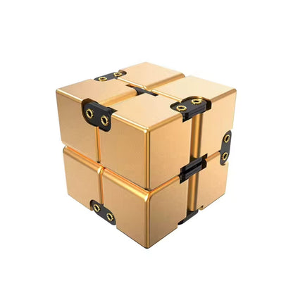 Guldfärgad Infinity Cube i aluminium med svarta leder, stilren fidgetleksak för händer och fokus.