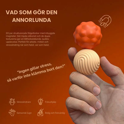 Hand håller beige och orangea fidgetbollar – fokus på textur och grepp.
