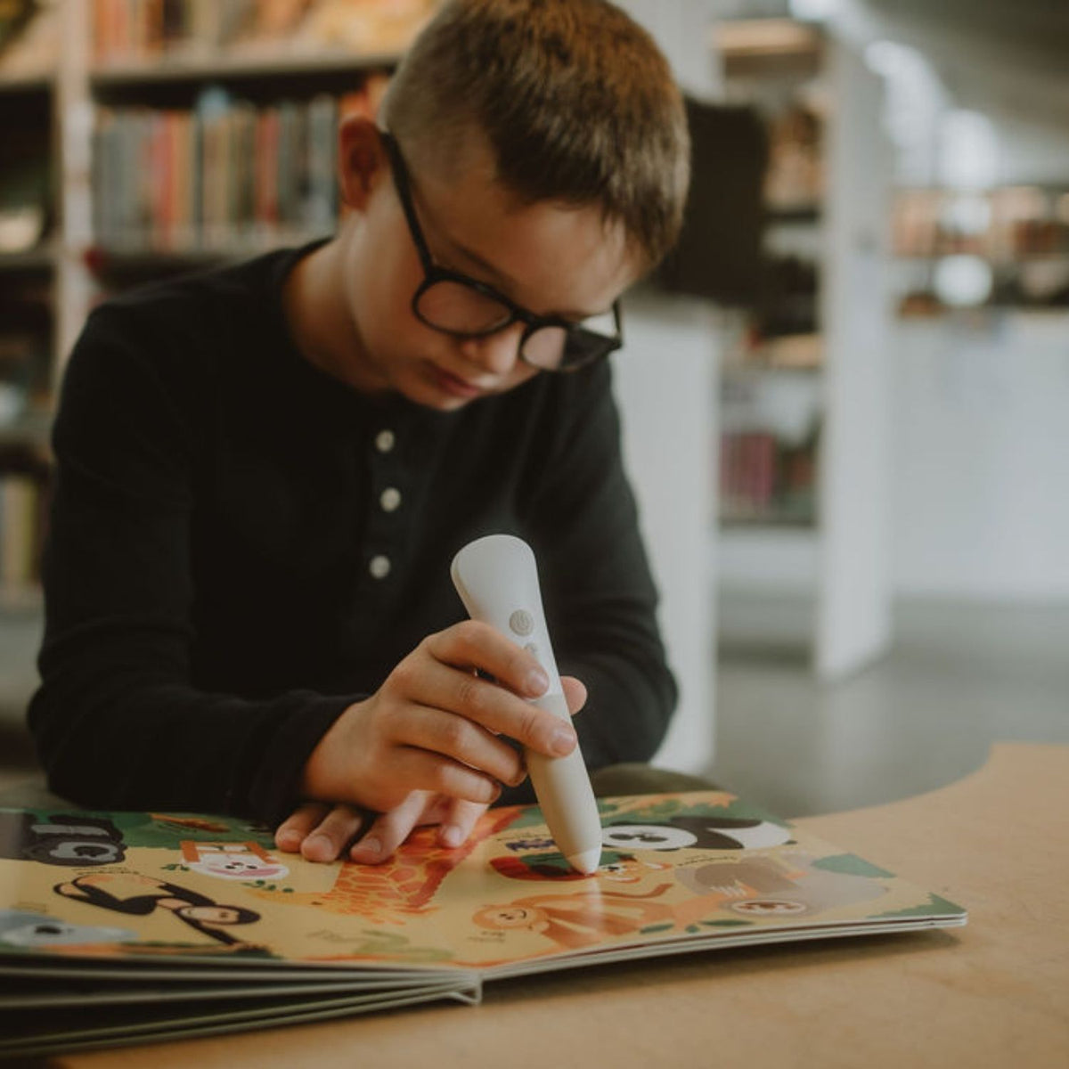 Pojke använder Readioo läspenna med boken "Mina första 100 ord: Djur".