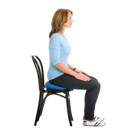 Person sitter på blå sittkudde Happyback 33 cm på en stol.