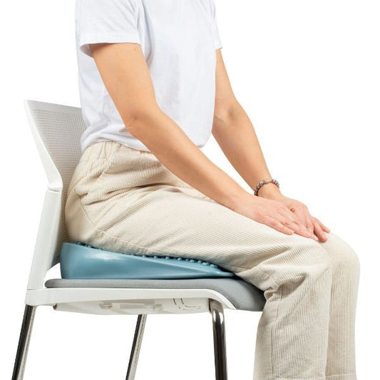 Person som sitter på kilformad sittkudde, ergonomiskt NPF-hjälpmedel för fokus och hållning