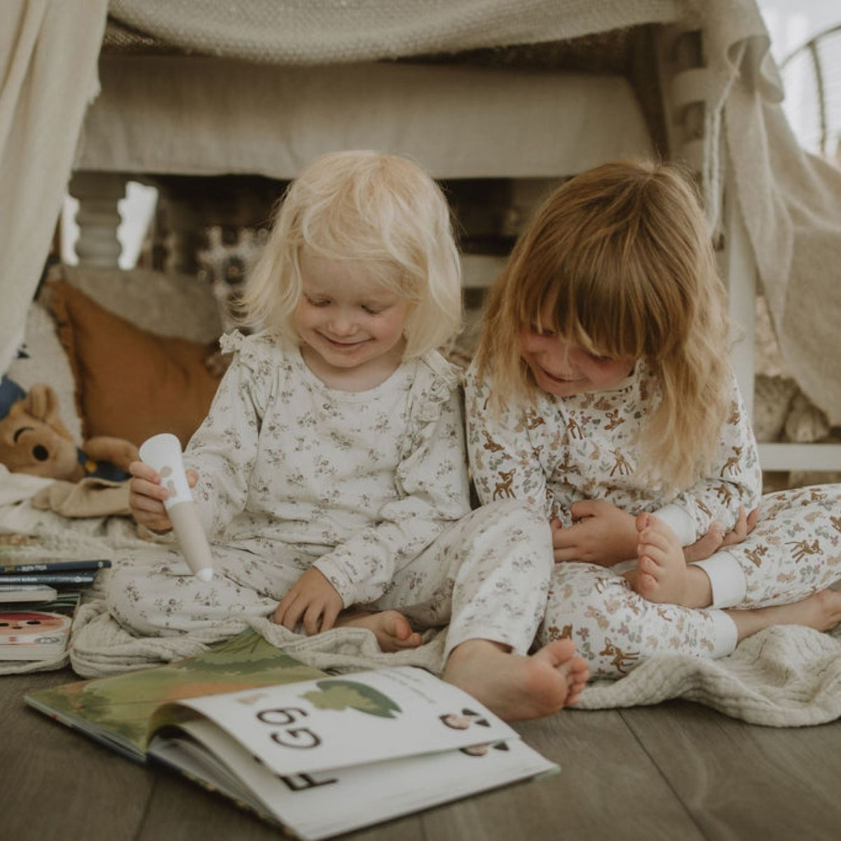 Två barn i pyjamas har lässtund tillsammans med Readioo-boken Bokstäver och läspennan.