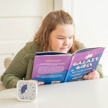 Barn läser bok med Time Timer MOD 120 min bredvid som stöd för tydlig tidsuppfattning och lugn