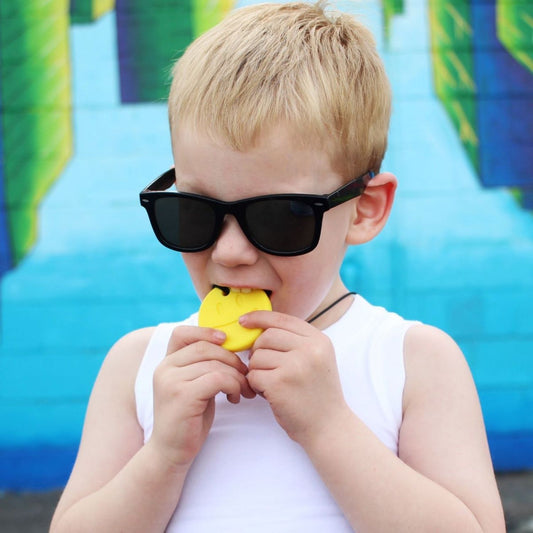 Barn tuggar på gult Smiley Face-tugghalsband för ADHD & autism.