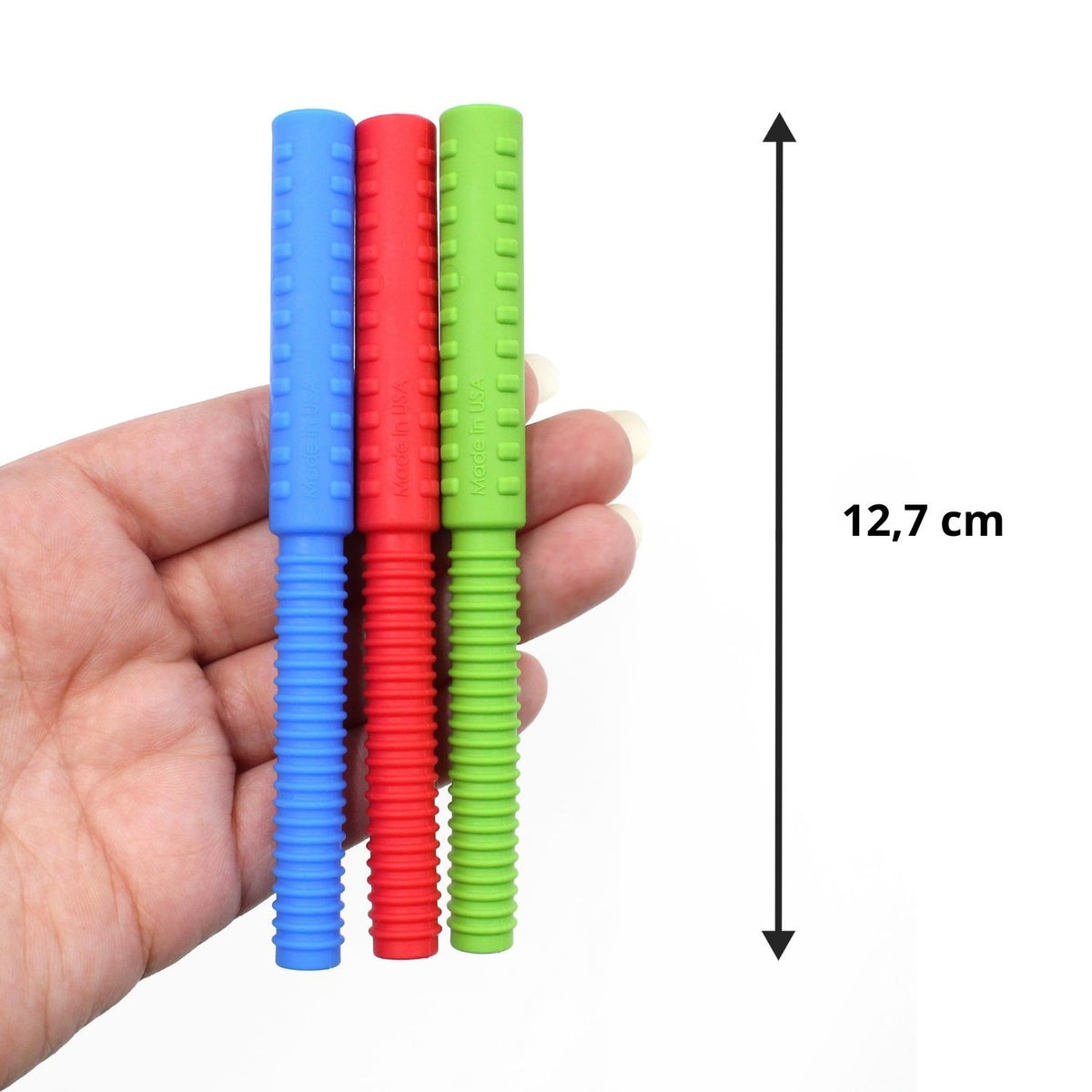 Hand håller tre tugghjälpmedel i olika färger, 12,7 cm långa.