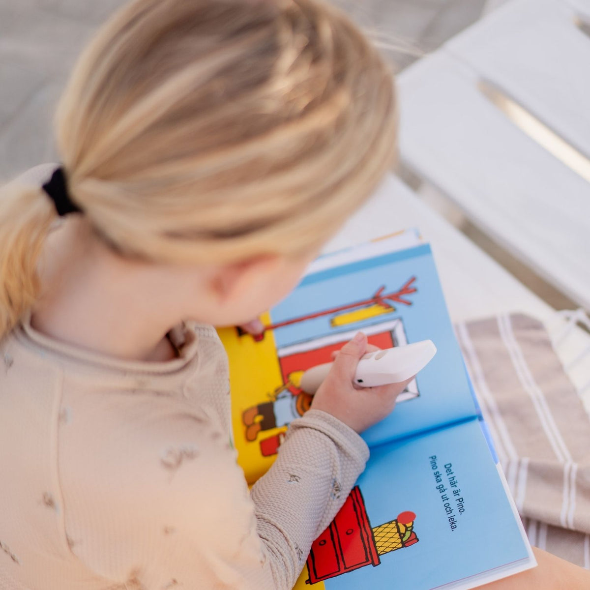 Barn använder Readioo läspenna i boken Vilket busigt väder Pino under interaktiv lässtund.